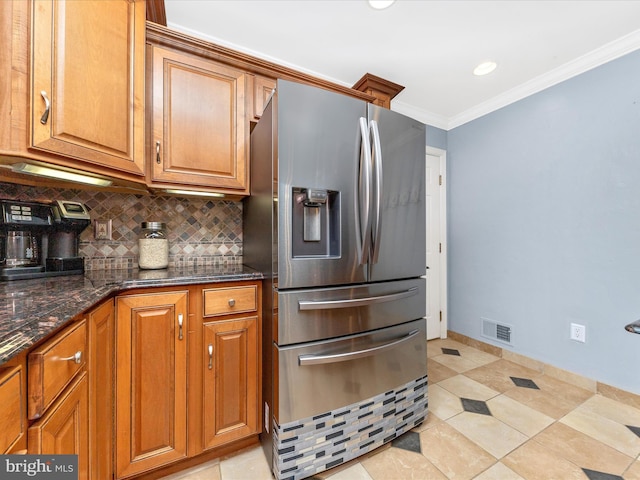 kitchen with stainless steel refrigerator with ice dispenser, dark stone countertops, crown molding, and light tile patterned flooring