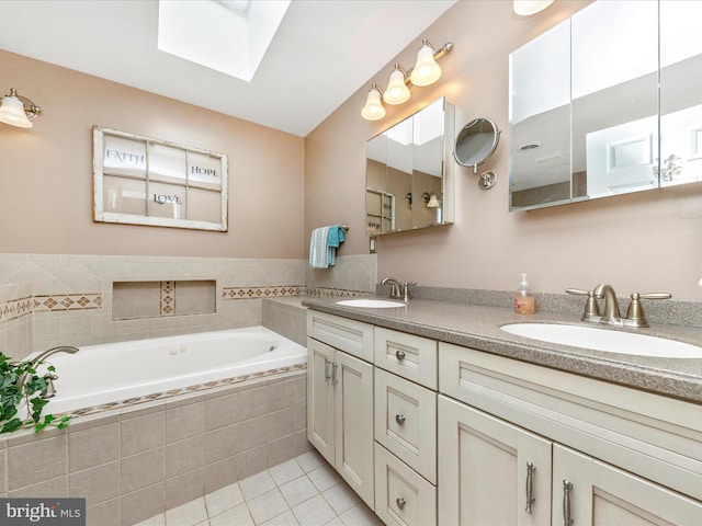 bathroom with a skylight, tile patterned flooring, a relaxing tiled tub, and vanity