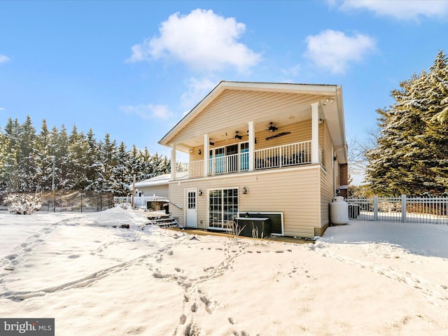 snow covered rear of property with a balcony and ceiling fan