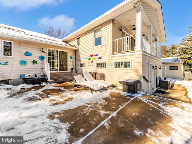 snow covered rear of property featuring a balcony