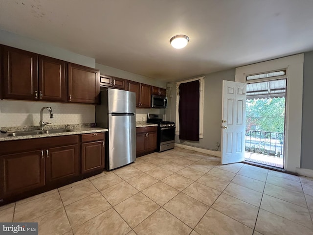 kitchen with light stone countertops, sink, stainless steel appliances, and dark brown cabinets