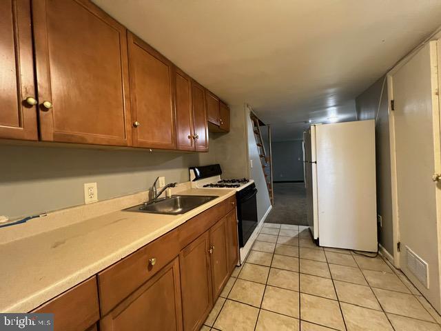 kitchen featuring white appliances, sink, and light tile patterned floors