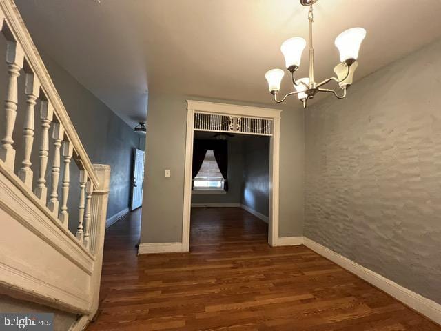 corridor with dark hardwood / wood-style flooring and a notable chandelier