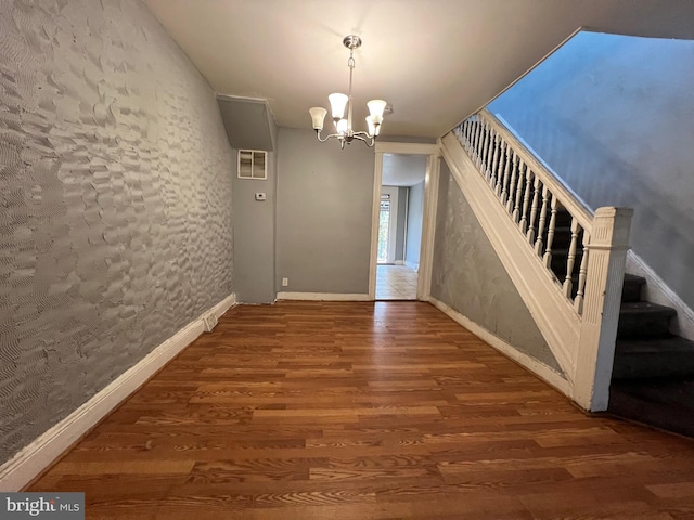 unfurnished dining area featuring a chandelier and hardwood / wood-style flooring