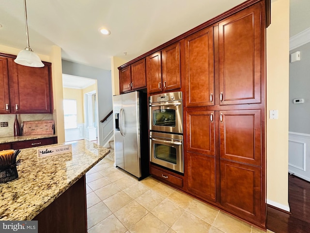 kitchen with light tile patterned flooring, appliances with stainless steel finishes, tasteful backsplash, hanging light fixtures, and light stone counters