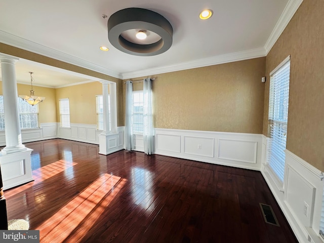 empty room featuring ornamental molding, a healthy amount of sunlight, dark hardwood / wood-style floors, and ornate columns