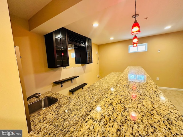 bar with pendant lighting, light stone countertops, and sink