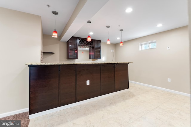 bar featuring dark brown cabinets, pendant lighting, and light stone counters