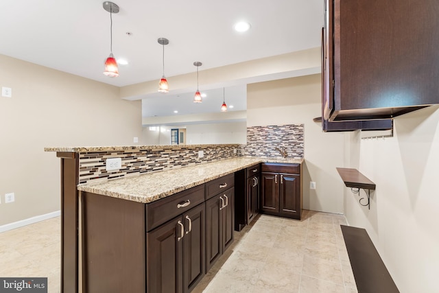 kitchen with sink, light stone counters, decorative backsplash, decorative light fixtures, and kitchen peninsula