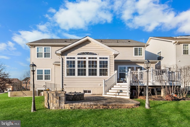 rear view of property featuring a wooden deck, a fire pit, and a lawn