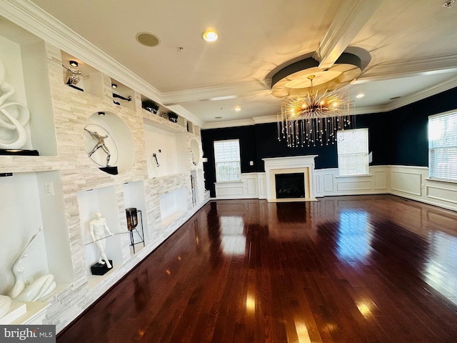 unfurnished living room with an inviting chandelier, ornamental molding, hardwood / wood-style flooring, and a wealth of natural light