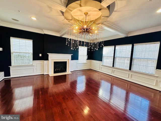 unfurnished living room featuring a notable chandelier, crown molding, plenty of natural light, and hardwood / wood-style floors