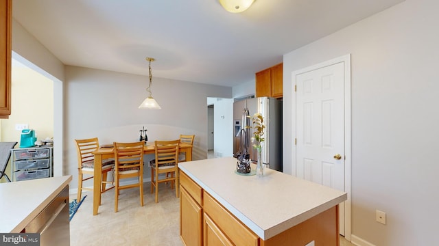 kitchen featuring hanging light fixtures, stainless steel fridge, and a kitchen island