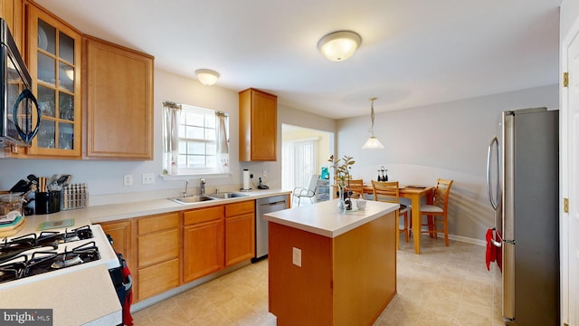 kitchen with sink, a kitchen island, appliances with stainless steel finishes, and decorative light fixtures