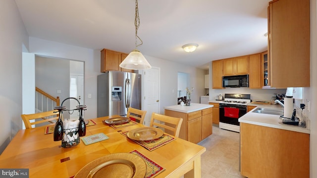 kitchen with pendant lighting, sink, stainless steel fridge with ice dispenser, a kitchen island, and white gas stove