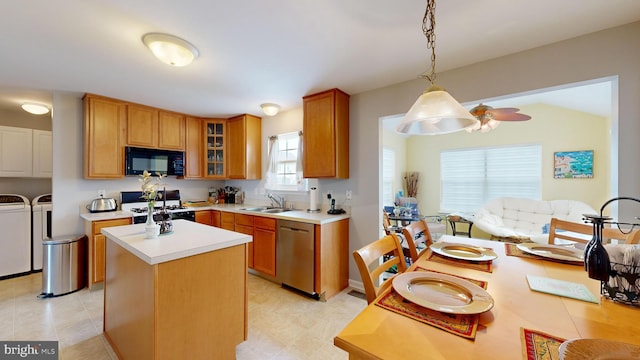 kitchen featuring pendant lighting, dishwasher, gas range, washing machine and clothes dryer, and a center island