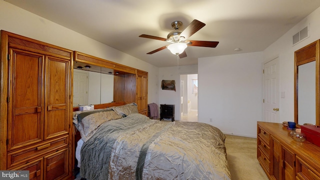 bedroom with ceiling fan, ensuite bathroom, and light colored carpet