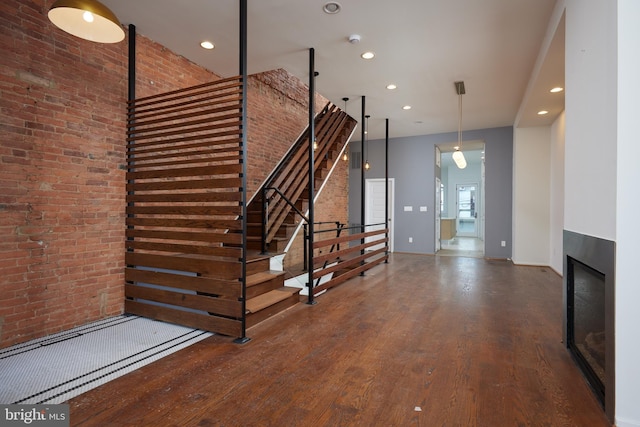 staircase featuring hardwood / wood-style flooring and brick wall