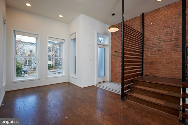 entryway with brick wall and dark hardwood / wood-style flooring