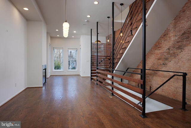 staircase with brick wall and wood-type flooring