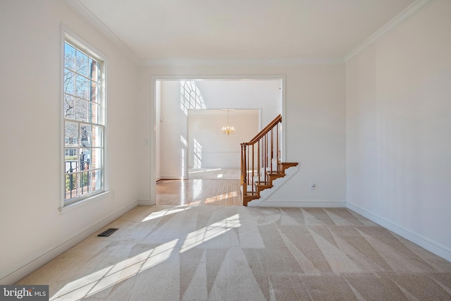 unfurnished room featuring a chandelier, carpet floors, ornamental molding, and visible vents