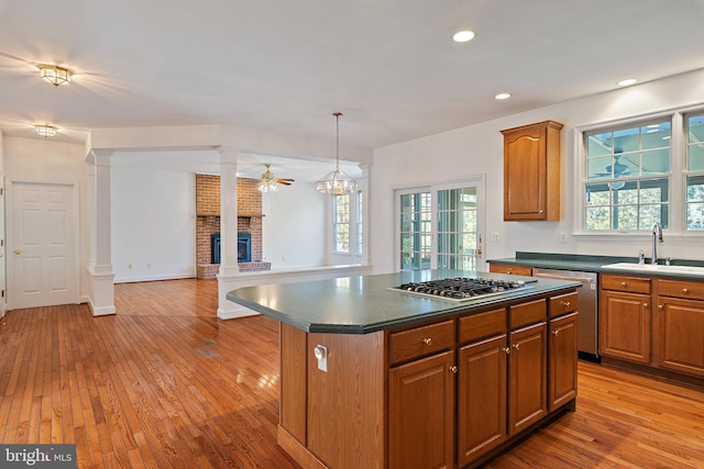 kitchen featuring appliances with stainless steel finishes, dark countertops, a sink, and ornate columns