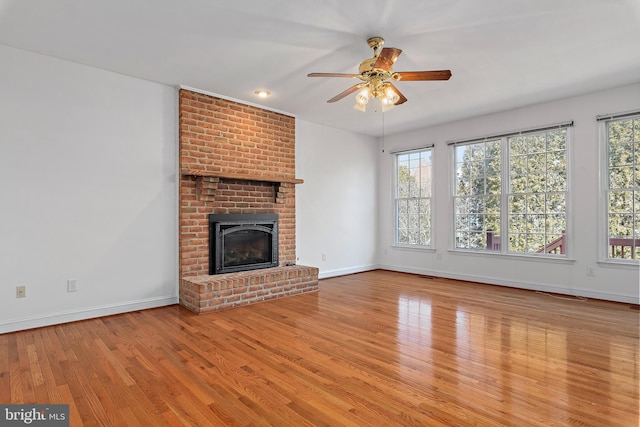 unfurnished living room with a brick fireplace, plenty of natural light, and wood finished floors