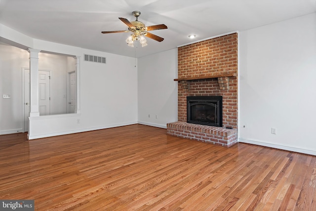 unfurnished living room with a ceiling fan, visible vents, a fireplace, and wood finished floors