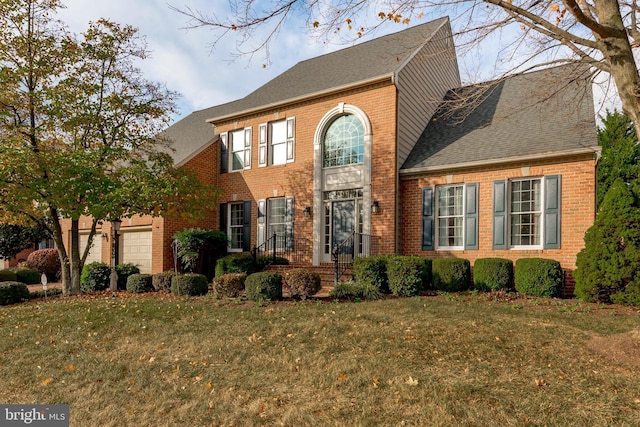 view of front of house featuring a garage, a shingled roof, a front lawn, and brick siding