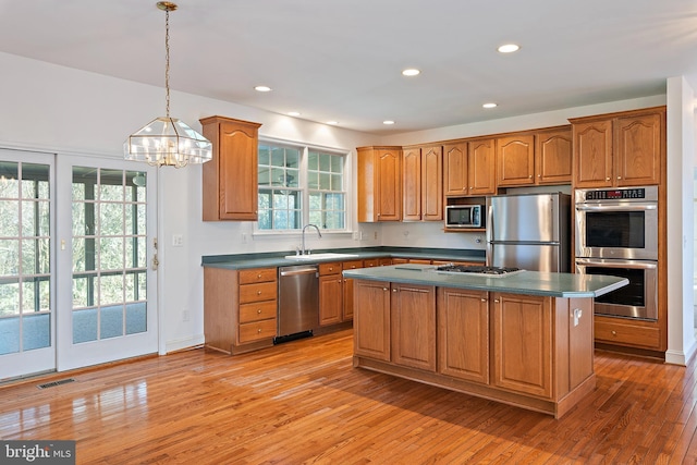 kitchen with a sink, visible vents, light wood-style floors, appliances with stainless steel finishes, and dark countertops