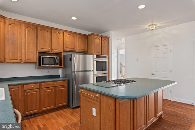 kitchen featuring brown cabinets, stainless steel appliances, and dark wood finished floors