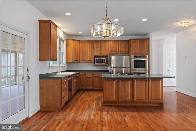 kitchen with appliances with stainless steel finishes, brown cabinetry, dark countertops, and a sink