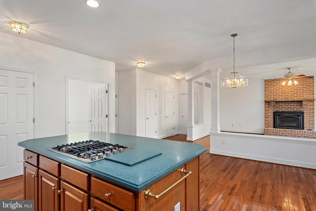 kitchen with brown cabinets, dark wood-style floors, stainless steel gas stovetop, and open floor plan