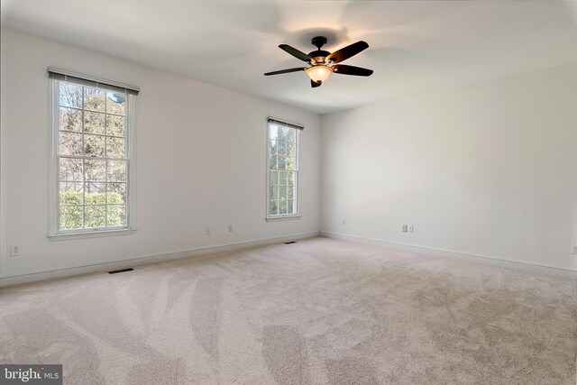 unfurnished room with a ceiling fan, carpet, visible vents, and baseboards