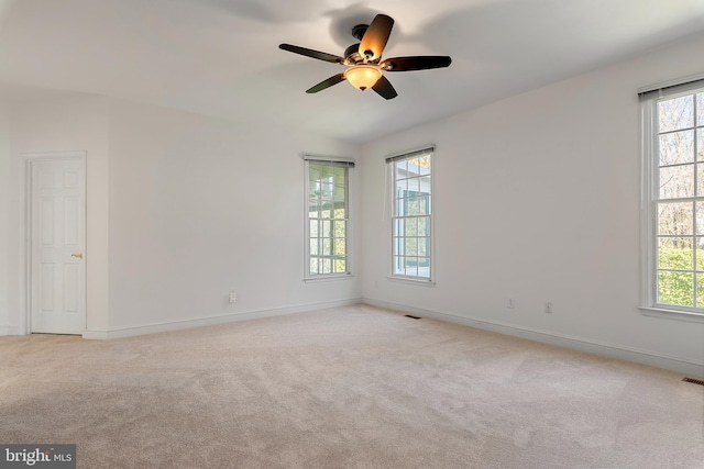 unfurnished room featuring plenty of natural light, visible vents, baseboards, and light colored carpet