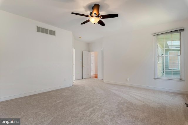 unfurnished room featuring light carpet, ceiling fan, visible vents, and baseboards