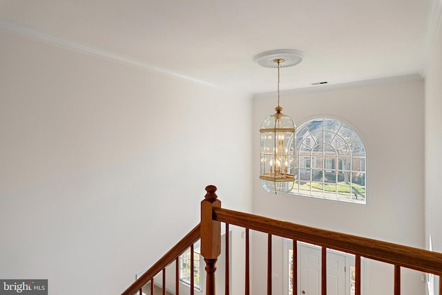 corridor with a chandelier, visible vents, ornamental molding, and an upstairs landing