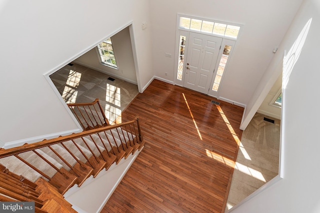 entrance foyer with stairway, visible vents, baseboards, and hardwood / wood-style floors