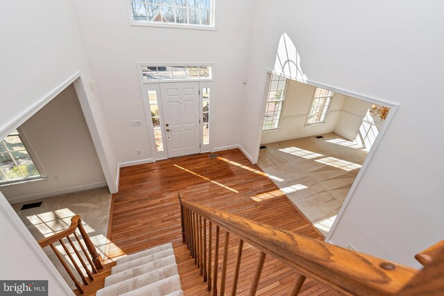 entryway featuring visible vents, stairway, a high ceiling, wood finished floors, and baseboards