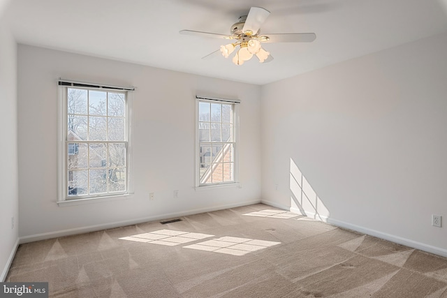 carpeted empty room featuring ceiling fan, visible vents, and baseboards