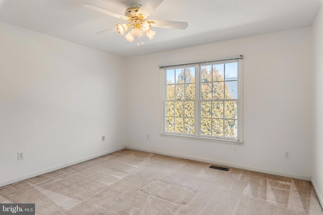 carpeted empty room featuring a ceiling fan, visible vents, and baseboards