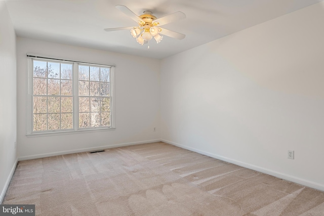 carpeted spare room with a ceiling fan, visible vents, and baseboards