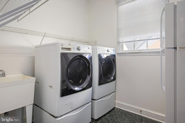 clothes washing area featuring a sink, laundry area, washing machine and dryer, and baseboards