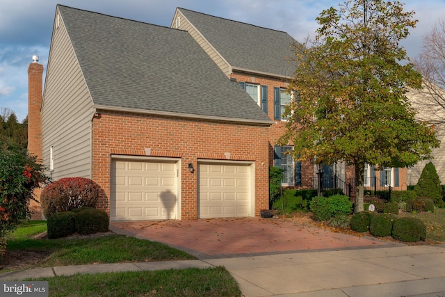 view of front facade featuring an attached garage, a shingled roof, a chimney, and brick siding