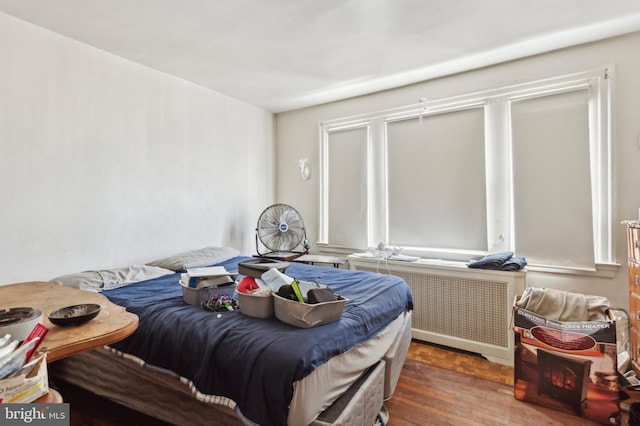 bedroom with radiator heating unit and dark hardwood / wood-style flooring