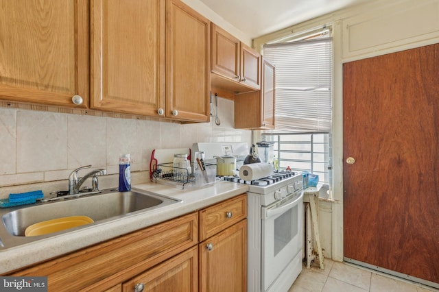 kitchen featuring light tile patterned floors, decorative backsplash, sink, and white range with gas stovetop