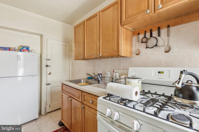 kitchen with light tile patterned flooring, sink, backsplash, and white appliances