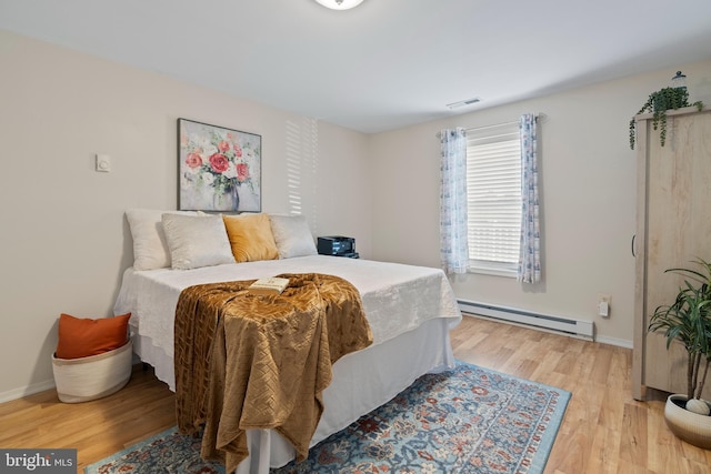 bedroom with baseboard heating and light hardwood / wood-style flooring