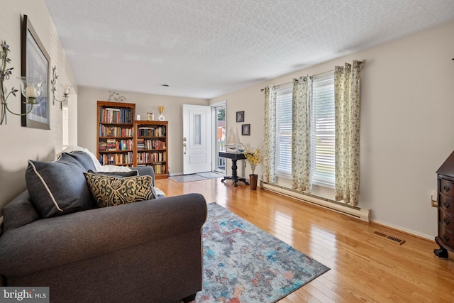 living room with a textured ceiling, light hardwood / wood-style floors, and baseboard heating