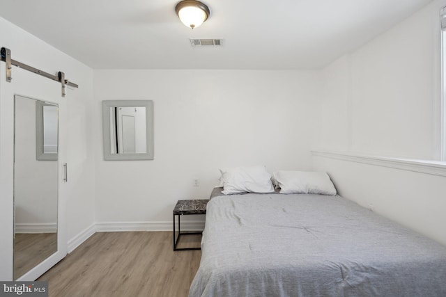 bedroom featuring light wood-type flooring and a barn door